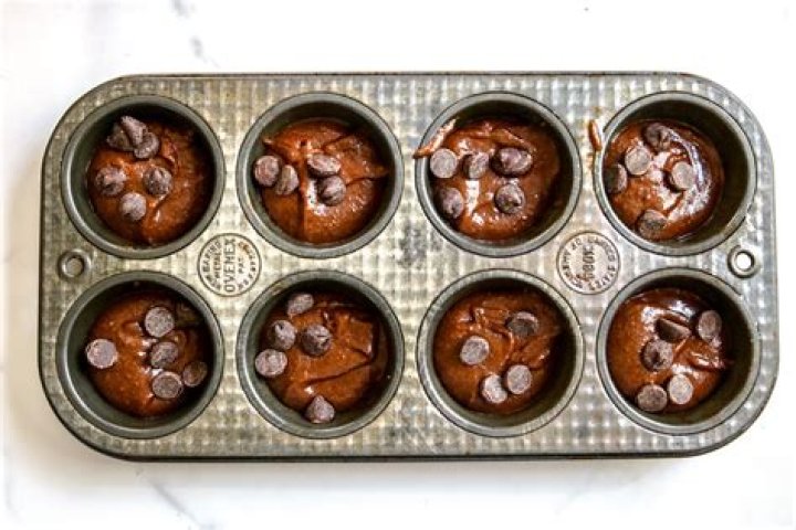 Brownies in a muffin tin topped with vanilla ice cream.