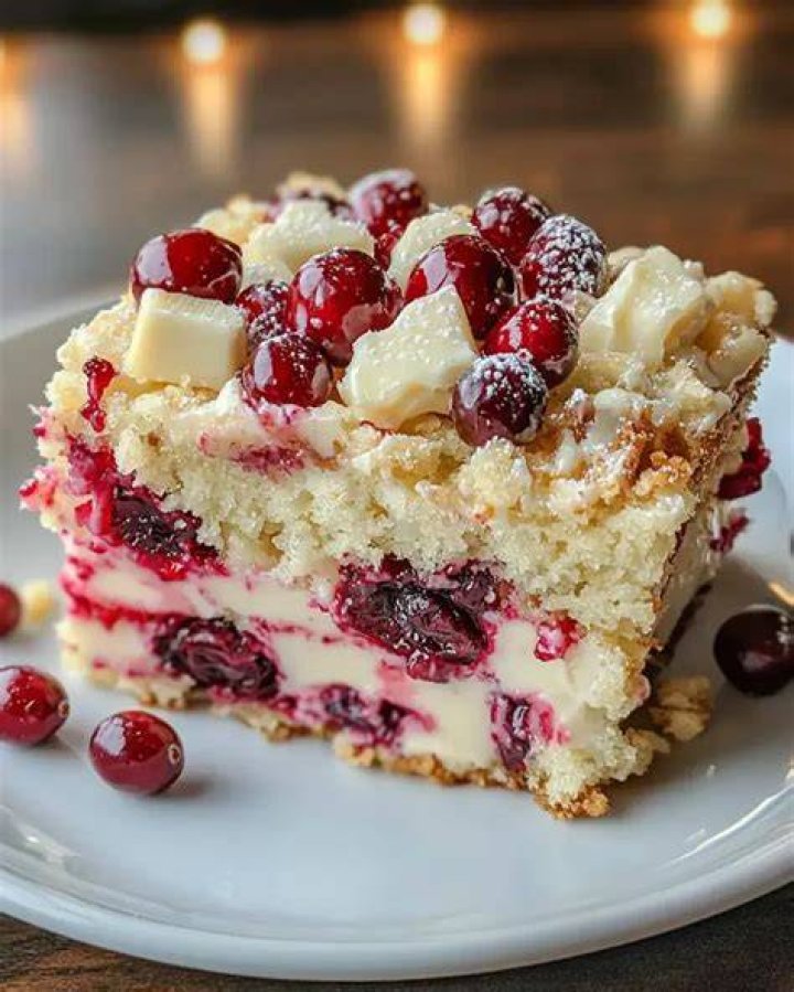 Cranberry cake on a white plate topped with yogurt.