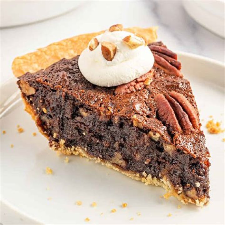 Ingredients for chocolate pecan pie - pie crust, syrup, sugar, chocolate chips, cocoa powder, pecans, vanilla, butter, eggs.