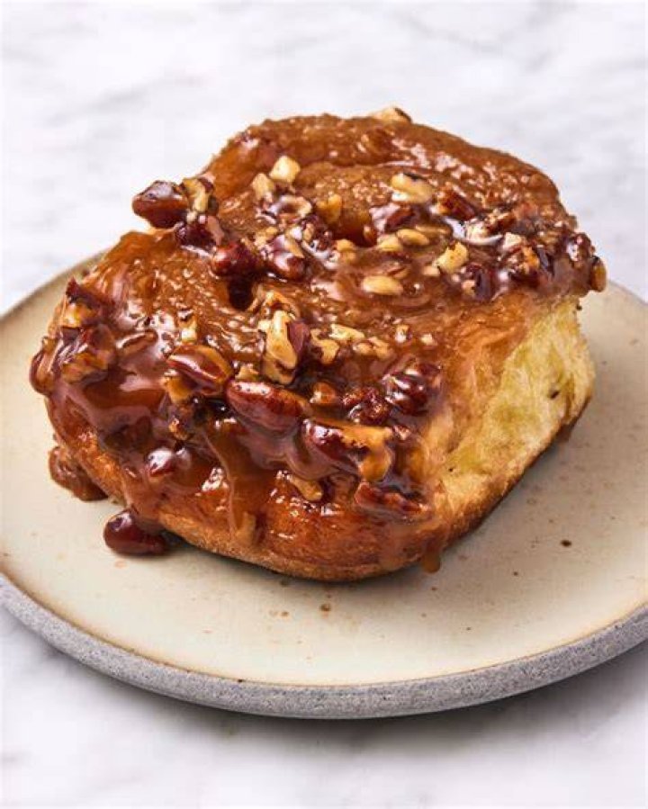 Sticky bun cut open on a white plate with a gold fork.