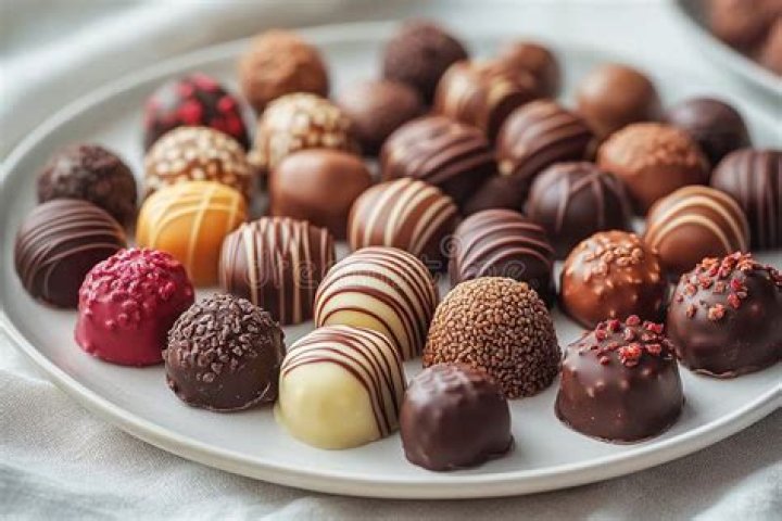 White plate filled with chocolate cookies filled with white chocolate chips.